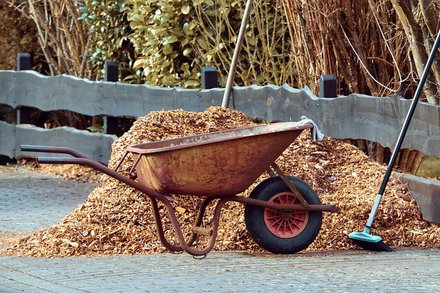 wheel barrow with a pile of bark next to it